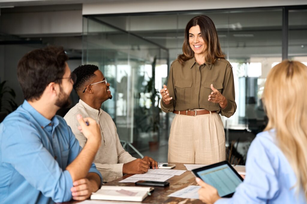 Happy middle aged business woman leader working with diverse team at meeting.